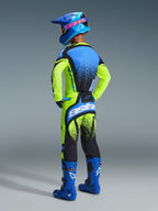 Motocross-Fahrer von hinten in der Alpinestars 2026 Techstar Nomur Hose, Gelb Fluo und UCLA Blau, kombiniert mit passendem Trikot, blauen Stiefeln und blauem Helm, zeigt das rückseitige „astars“-Logo und schwarzes Splatter-Design.