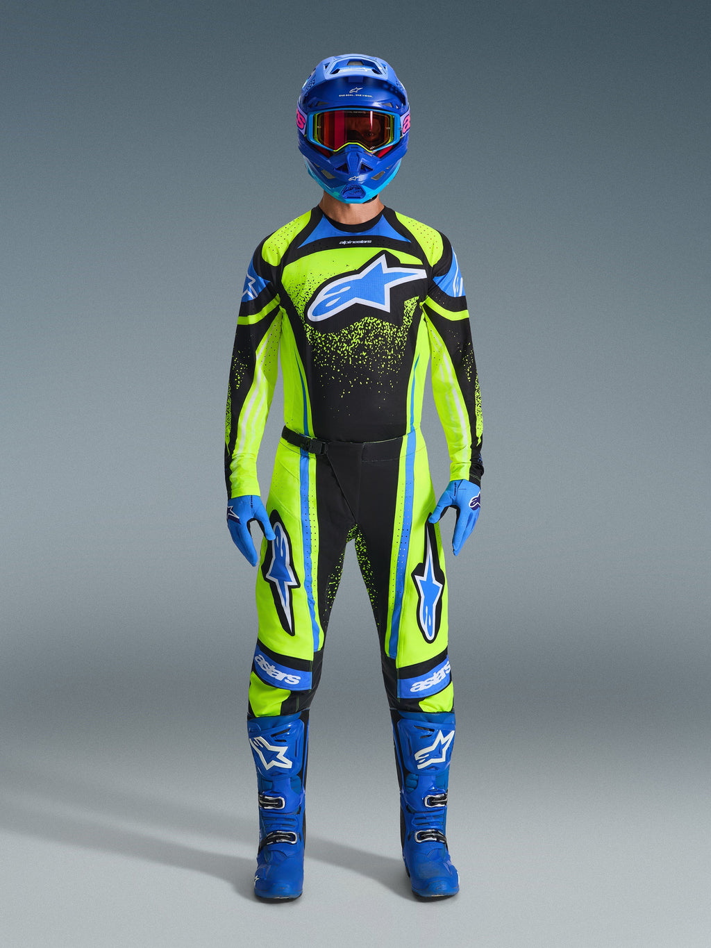 Motocross-Fahrer in kompletter Rennausrüstung, Alpinestars 2026 Techstar Nomur Hose und Trikot in Gelb Fluo und Dunkelblau mit blauen Akzenten und Logos, kombiniert mit blauem Helm, Handschuhen und Stiefeln für einen koordinierten Offroad-Rennlook.
