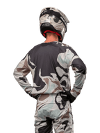 Motocross-Fahrer in der Rückansicht, Alpinestars 2024 Racer Tactical Jersey in Iron Camo Dust Gray, passende Camouflage-Hose und Helm, Hände an den Hüften, abgestimmte Offroad-Rennausrüstung