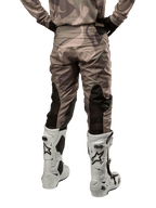 Alpinestars 2024 Racer Tactical Hose, Motocross-Hose, Military Green Camo Brown, Rückansicht mit Camouflage-Muster und schwarzen atmungsaktiven Stretch-Einsätzen an den Unterschenkeln, getragen mit weißen Motocross-Stiefeln, strapazierfähige technische Ausrüstung für das Offroad-Fahren