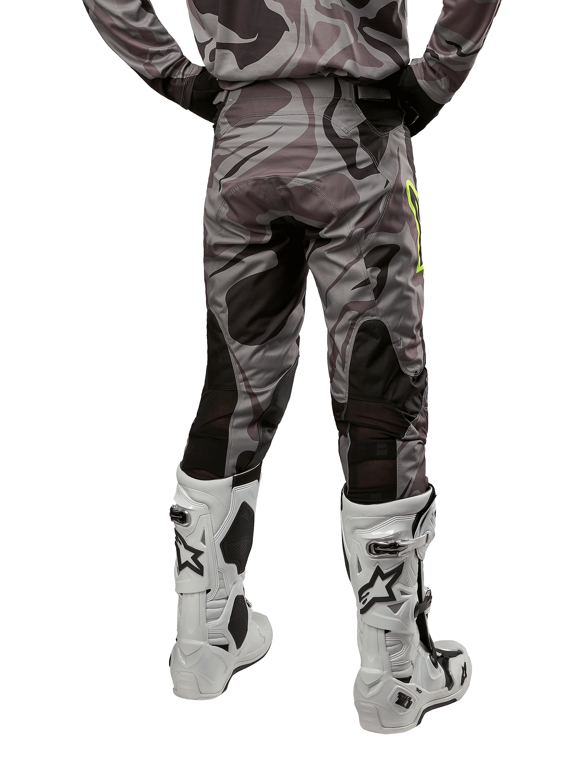 Alpinestars 2024 Racer Tactical Hose, Motocross-Hose, Cast Gray Camo Magnet, Rückansicht zeigt Camouflage-Muster und schwarze atmungsaktive Stretch-Zonen, getragen mit weiß-schwarzen Motocross-Stiefeln, entwickelt für Offroad-Rennsport.