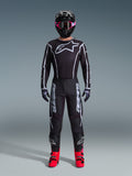 Alpinestars 2026 Fluid Apex Ausrüstungsset, Motocross-Outfit, Schwarz mit grauen Akzenten, Jersey mit großem weißem Astars-Logo, passende Hose mit markantem Branding, schwarzer Helm mit rosa Brille und leuchtend roten Stiefeln, komplettes Offroad-Rennset
