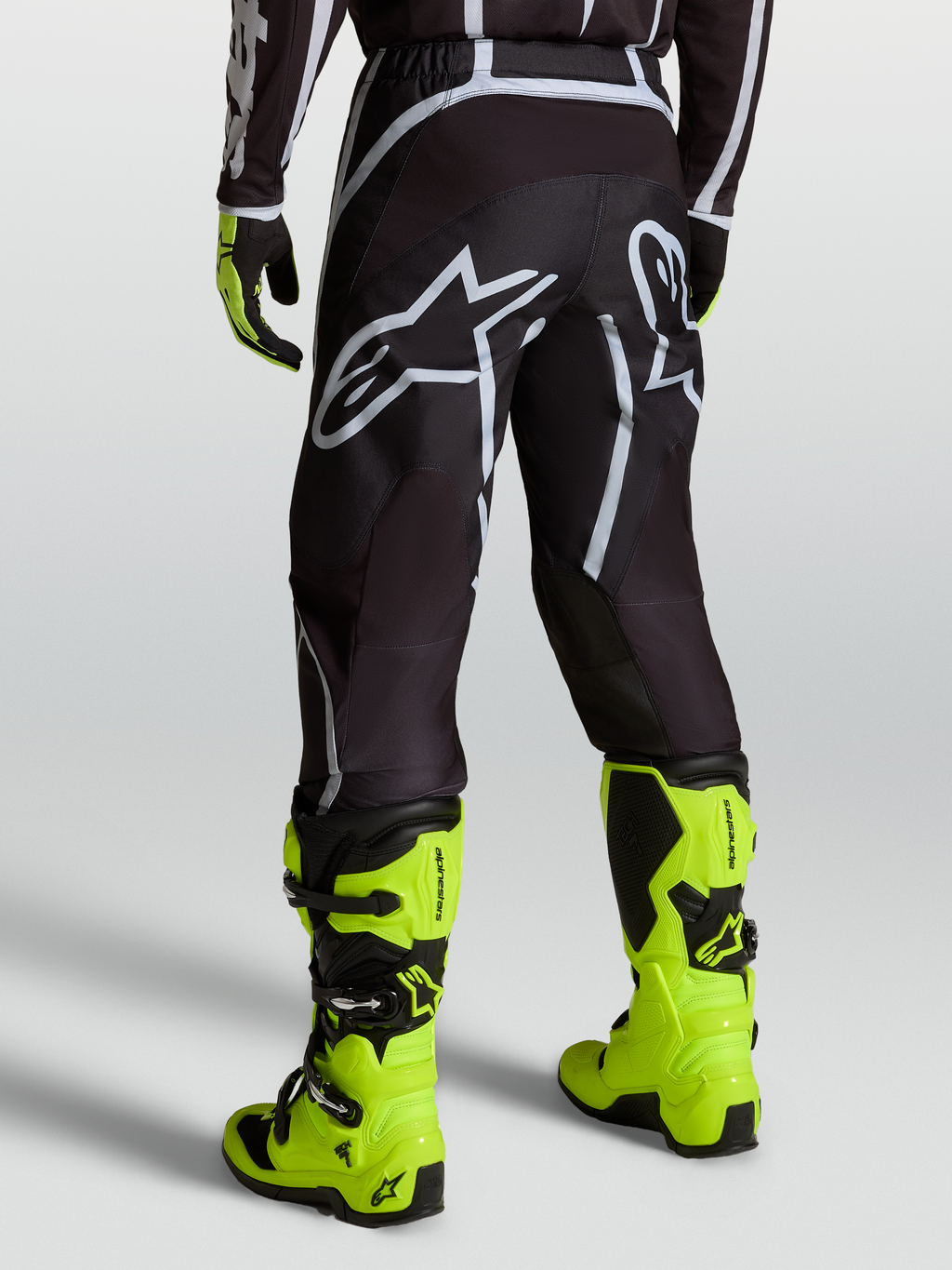 Alpinestars Fluid Apex V2 Hose, Motocross-Hose für Herren, Schwarz und Silber, getragen mit neongelben Motorradstiefeln, Offroad-Ausrüstung für MX-Fahrer.