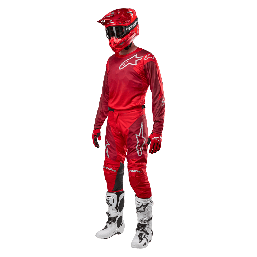Motocross-Fahrer in kompletter Rennausrüstung, Alpinestars 2024 Racer Hoen Hose und Trikot in Mars Red Burgundy, roter Helm, rote Handschuhe und weiß-schwarze Stiefel, abgestimmtes Outfit für Offroad-Rennen