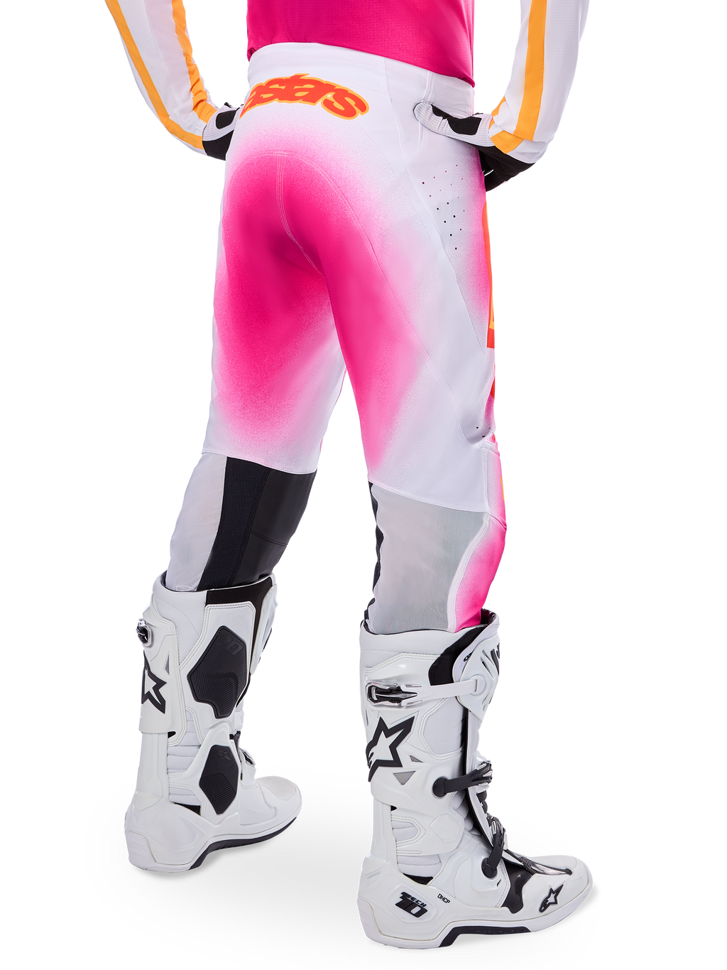 Alpinestars Supertech AFD MIG Limited Edition Motocross-Hose, Pink und Weiß, Rückansicht mit einem leuchtenden pinkfarbenen Verlaufs-Sprüheffekt, orangefarbenes Logo am hinteren Bund, kombiniert mit weiß-schwarzen Tech 10 Stiefeln, professionelle Offroad-Rennbekleidung