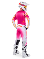 Motocross rider seen from the back wearing the Limited Edition Supertech AFD MIG Gear Set, pink jersey with orange accents, white pants with pink gradient and orange Alpinestars branding, white helmet with pink graphics and orange goggles, white and black boots, professional off-road racing kit