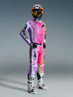 Motocross rider wearing the Alpinestars 2026 Racer Air Portl Jersey and matching pants, vibrant pink, purple, and orange multicolor gradient with white accents, coordinated colorful helmet and yellow goggles, white and black boots, complete racing outfit for off-road performance