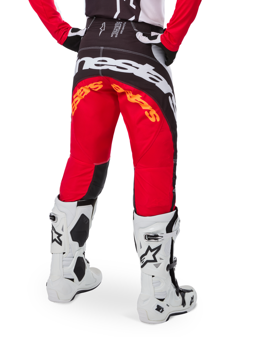 Alpinestars Limited Edition Techstar Deep Hose, Motocross-Hose, Schwarz, Weiß und High Red, Rückansicht mit markantem weißen Alpinestars-Logo auf dem Gesäß und orangefarbenem Branding, getragen mit weißen technischen Stiefeln für professionellen Offroad-Rennsport.
