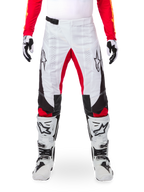 Alpinestars Limited Edition Techstar Deep Hose, Motocross-Hose, Weiß mit schwarzen und roten Akzenten, Stern-Logo und Laser-Perforationen, getragen mit weißen Motocross-Stiefeln und Handschuhen, strapazierfähiges technisches Material für den Offroad-Sport