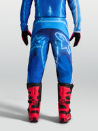 Alpinestars Fluid Kepler Hose, Herren Motocross-Hose in Blau, 600D-Polygewebe, Rückansicht am Model mit roten MX-Stiefeln.