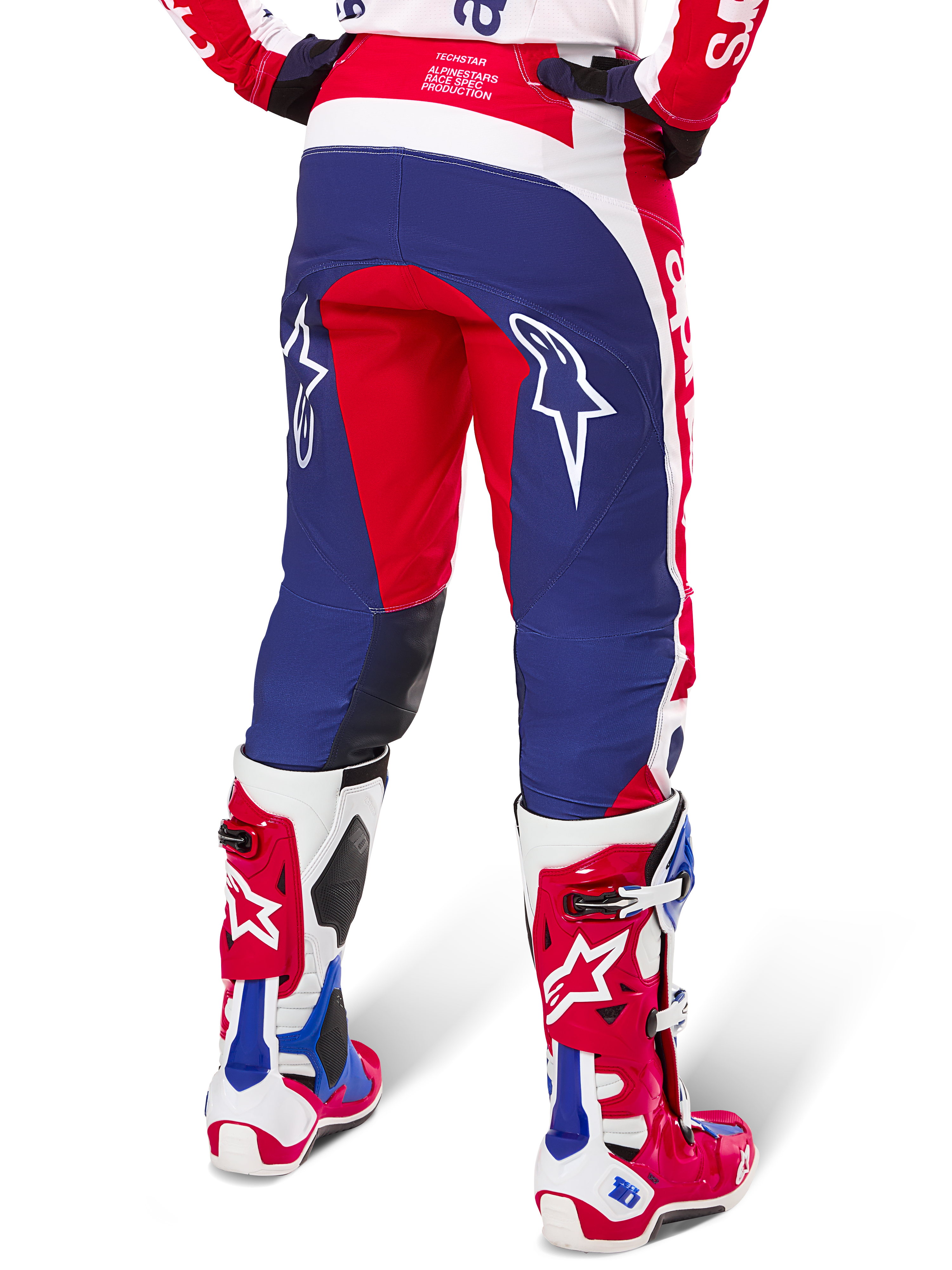 Alpinestars Limited Edition Techstar Fortitude Hose, Motocross-Hose, Rot, Weiß und Blau, Rückansicht getragen mit passenden rot-weißen Stiefeln, weiße Stern-Logos auf den Oberschenkeln, strapazierfähiges Multi-Panel-Design für professionellen Offroad-Rennsport