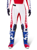 Alpinestars Limited Edition Techstar Fortitude Hose, Motocross-Hose, Hellrot, Weiß und Blau, getragen mit passender Ausrüstung einschließlich blauer Schutzstiefel und Handschuhe, weißes Chassis mit roten Grafiken, schwarze Leder-Knieeinsätze und lasergeschnittene Perforationen, professionelle Offroad-Rennbekleidung