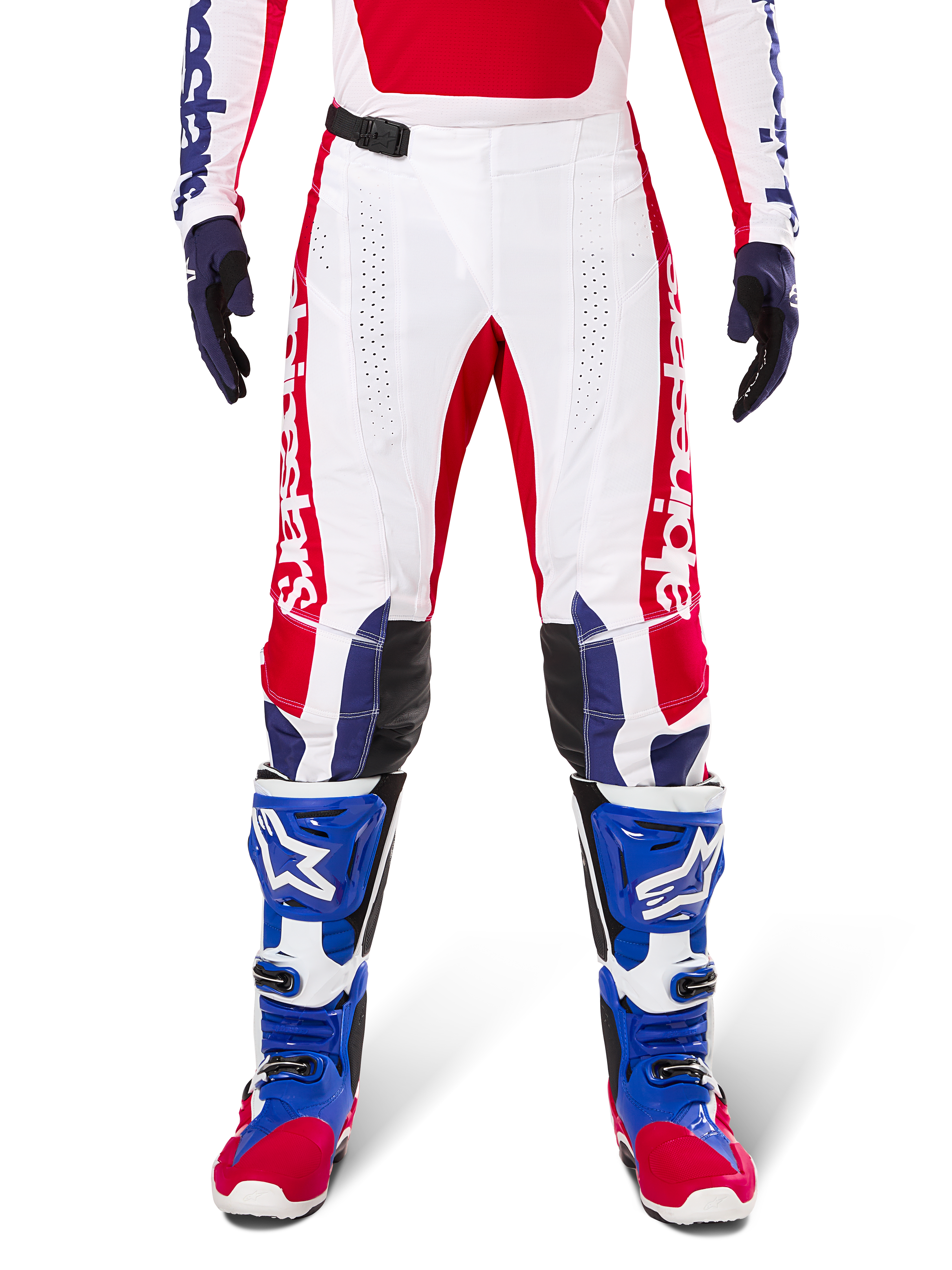 Alpinestars Limited Edition Techstar Fortitude Hose, Motocross-Hose, Hellrot, Weiß und Blau, getragen mit passender Ausrüstung einschließlich blauer Schutzstiefel und Handschuhe, weißes Chassis mit roten Grafiken, schwarze Leder-Knieeinsätze und lasergeschnittene Perforationen, professionelle Offroad-Rennbekleidung
