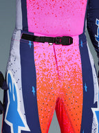 Alpinestars Limited Edition Supertech Records Hose, Motocross-Hose, Mehrfarbig Pink und Orange mit marineblauen Seiteneinsätzen, Nahaufnahme des Hosenbundes mit schwarzer, selbstverriegelnder SX1-Magnetschnalle, Ripstop-Gewebe mit Splatter-Grafiken und lasergeschnittenen Perforationen.