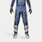 Alpinestars 2024 Fluid Lurv Hose, Motocross-Hose, Hellblau und Schwarz, getragen mit weißen und schwarzen Rennstiefeln und passenden Handschuhen, mit markanten schwarzen Stern-Logos auf den Oberschenkeln, ergonomisches Design für Offroad-Performance