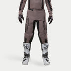 Alpinestars 2024 Fluid Lurv Hose, Motocross-Hose, Mud Black, getragen mit passendem Jersey, schwarzen Handschuhen und weißen Stiefeln, mit großen schwarzen Logos auf den Oberschenkeln, ergonomischer Passform und strapazierfähigem Material für Offroad-Rennen