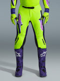 Alpinestars 2026 Supertech Vista Hose, Motocross-Hose, Neongelb, Lila und Schwarz, kombiniert mit passenden Handschuhen und lila Stiefeln, mit großen Logos mit Farbverlauf auf den Oberschenkeln, perforierten Zonen zur Belüftung und einem professionellen athletischen Design für den Offroad-Rennsport