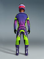 Alpinestars 2026 Supertech Vista Hose, Motocross-Hose, Gelb, Lila und Schwarz, Rückansicht eines Motocross-Fahrers in kompletter Rennausrüstung mit einem Jersey mit lila Farbverlauf und lila Stiefeln, dynamisches sportliches Design für professionellen Offroad-Rennsport