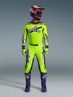 Alpinestars 2026 Supertech Vista Hose, Motocross-Hose, Neongelb mit lila und schwarzen Akzenten, getragen als Teil eines abgestimmten Rennausrüstungs-Sets mit passendem Jersey, Helm und lila Stiefeln, professionelle athletische Passform und auffällige Logos für Offroad-Performance