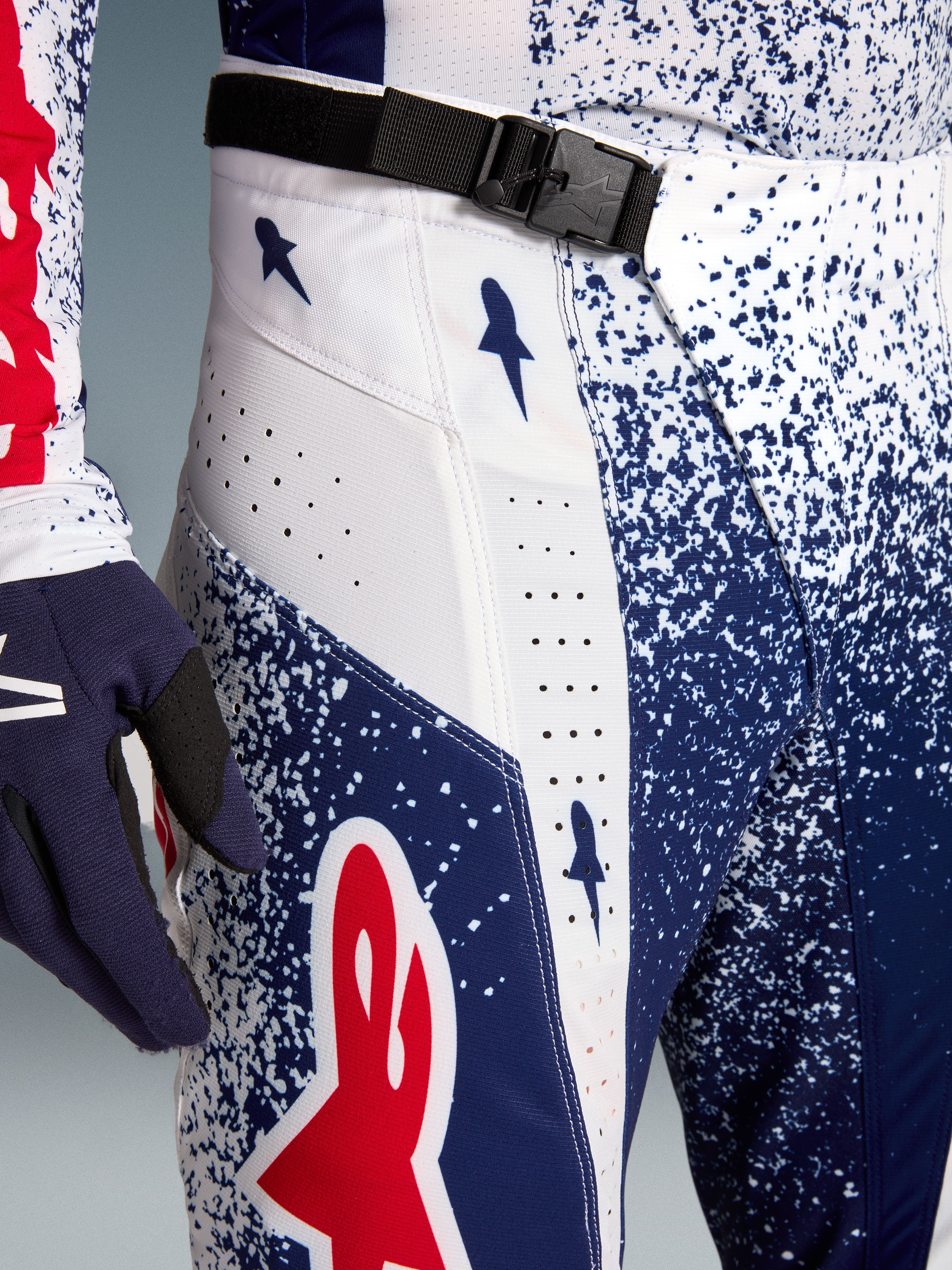 Alpinestars Techstar Unity motocross pants in red, white, and blue with SX2 magnetic buckle and laser perforations.