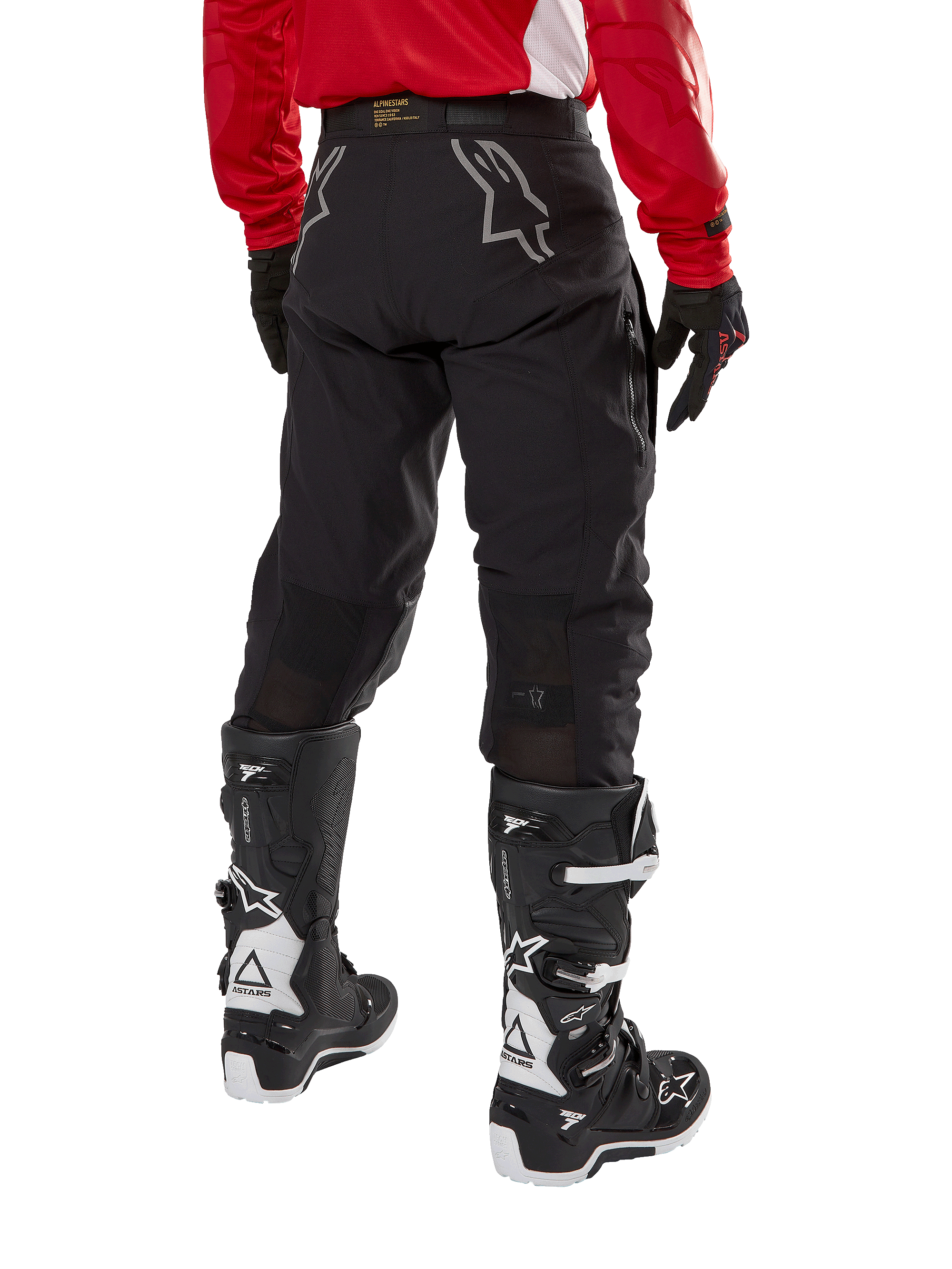 Alpinestars Techdura Hose, Offroad-Enduro-Hose, Schwarz, Rückansicht mit grauen Stern-Logos auf dem Gesäß, getragen mit einem roten langärmeligen Trikot und schwarz-weißen Tech 7 Stiefeln, robuste Textilkonstruktion für Abenteuerfahrten