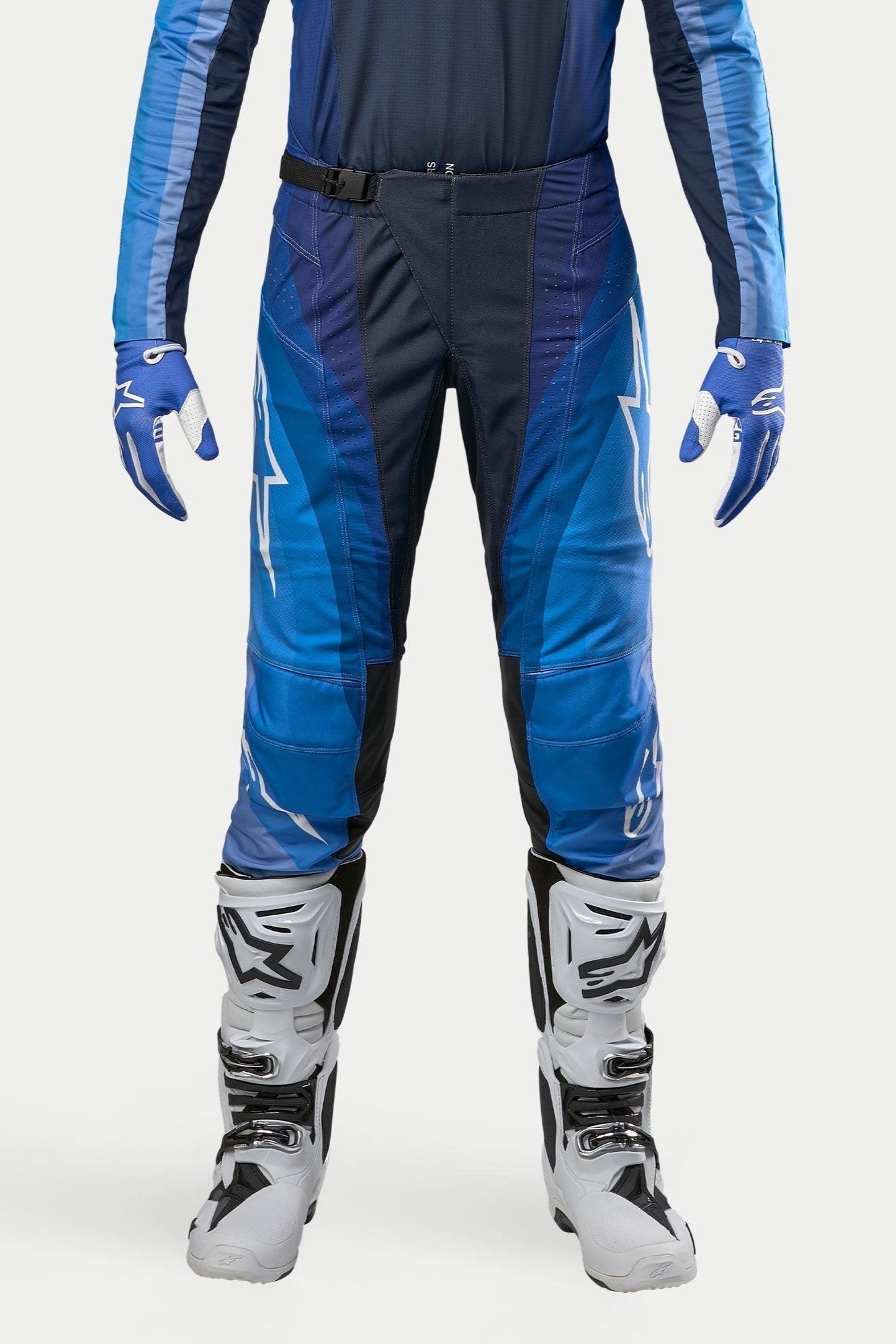 Alpinestars 2024 Techstar Pneuma Hose, Motocross-Hose, Dunkelblau und Hellblau, getragen mit passendem blauem Trikot und weißen Stiefeln, mit weißem Alpinestars-Branding und Magnetverschluss, konzipiert für professionelle Offroad-Performance