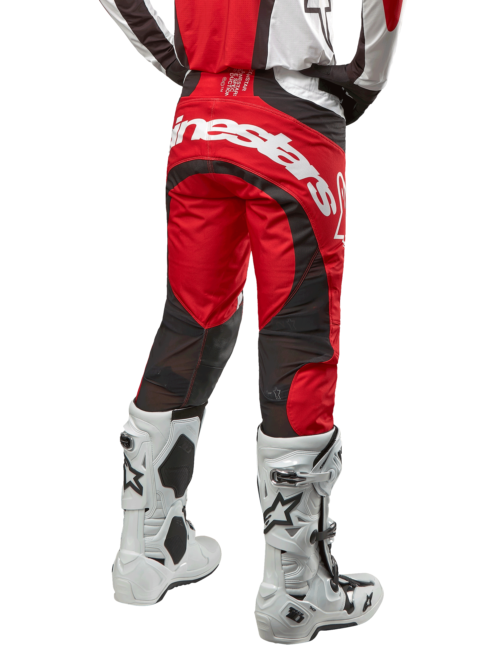Alpinestars 2024 Techstar Ocuri Hose, Motocross-Hose, Mars Red, Weiß und Schwarz, Rückansicht mit großem weißem Alpinestars-Logo auf dem Gesäß, schwarze Mesh-Belüftungseinsätze, getragen mit weiß-schwarzen Motocross-Stiefeln, athletisches Race-Fit-Design für das Offroad-Fahren