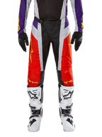 Alpinestars 2024 Techstar Ocuri Hose, Motocross-Hose, Hot Orange, Lila und Schwarz, getragen mit passendem Jersey, schwarzen Handschuhen und weißen Stiefeln, mit leuchtend orangen Frontpaneelen, lila Akzenten an der Taille und perforierten grauen Einsätzen, technisches Design für den Offroad-Rennsport
