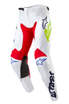 Alpinestars 2024 Racer Hana Pants, Motocross Pants, White Multicolor, featuring red and black inner knee panels, blue Astars logos and neon yellow branding, pre-curved design with ratchet waist closure, durable textile gear for off-road racing
