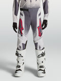 Alpinestars Jugend Supertech Swan Hose, Motocross-Rennhose in Grau und Lila mit roten Akzenten, getragen mit weißen Stiefeln.