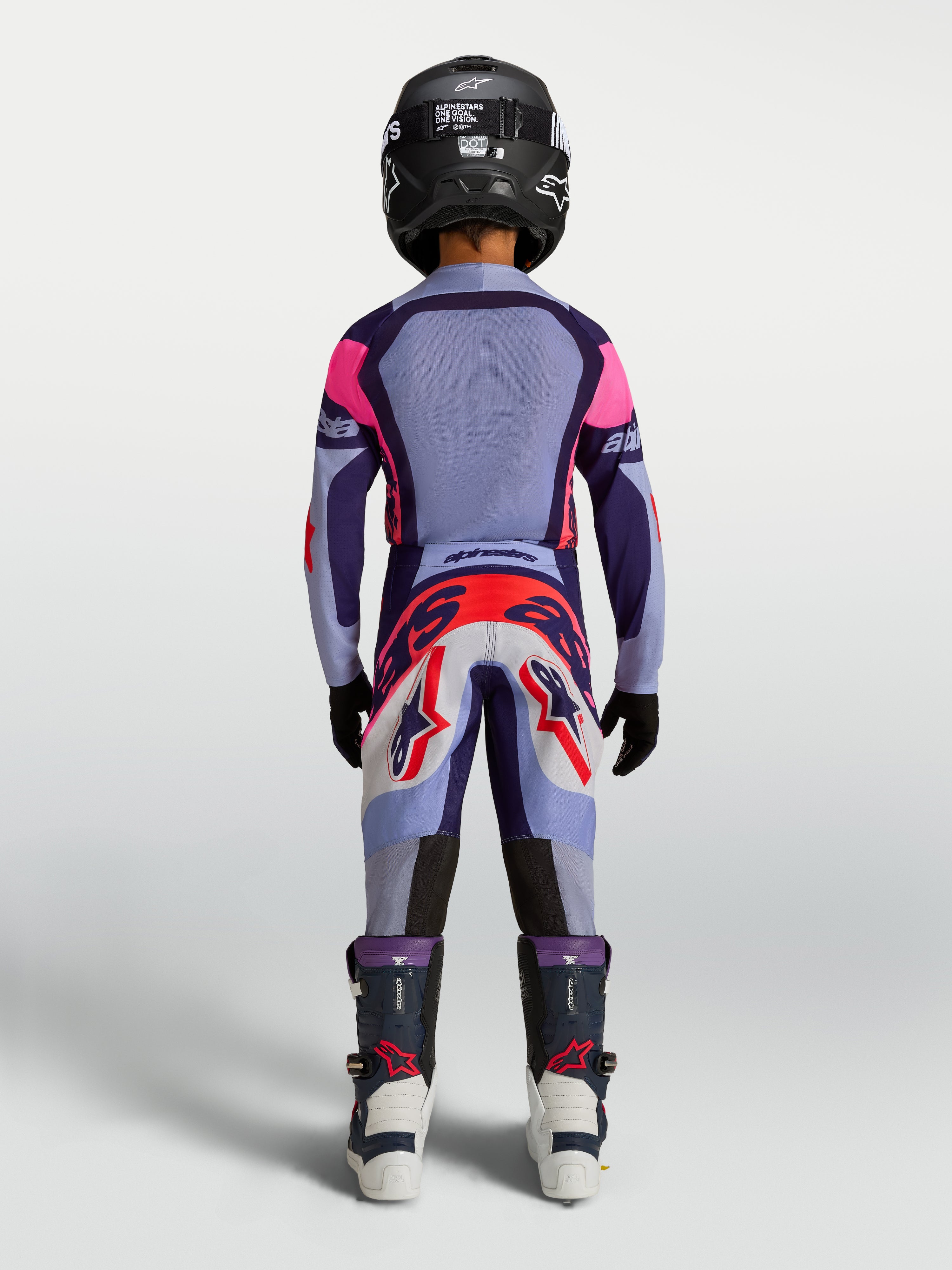 Alpinestars Jugend Supertech Dyna Hosen, Motocross-Rennhose für Kinder, Hellviolett und Lila, Rückansicht am jungen Fahrer mit Helm und Stiefeln, strapazierfähige MX-Bekleidung