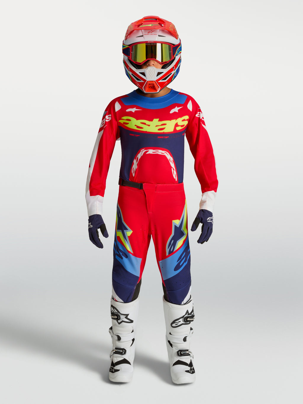 Alpinestars Jugend Supertech Dyna Hose, Motocross-Ausrüstungsset in Rot und Blau mit weißen Motorradstiefeln und Helm.