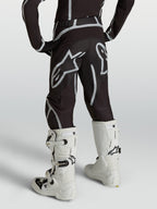 Alpinestars Jugend Fluid Apex V2 Hose, Motocross-Hose, Schwarz und Silber, Rückansicht mit weißen Motocross-Stiefeln.