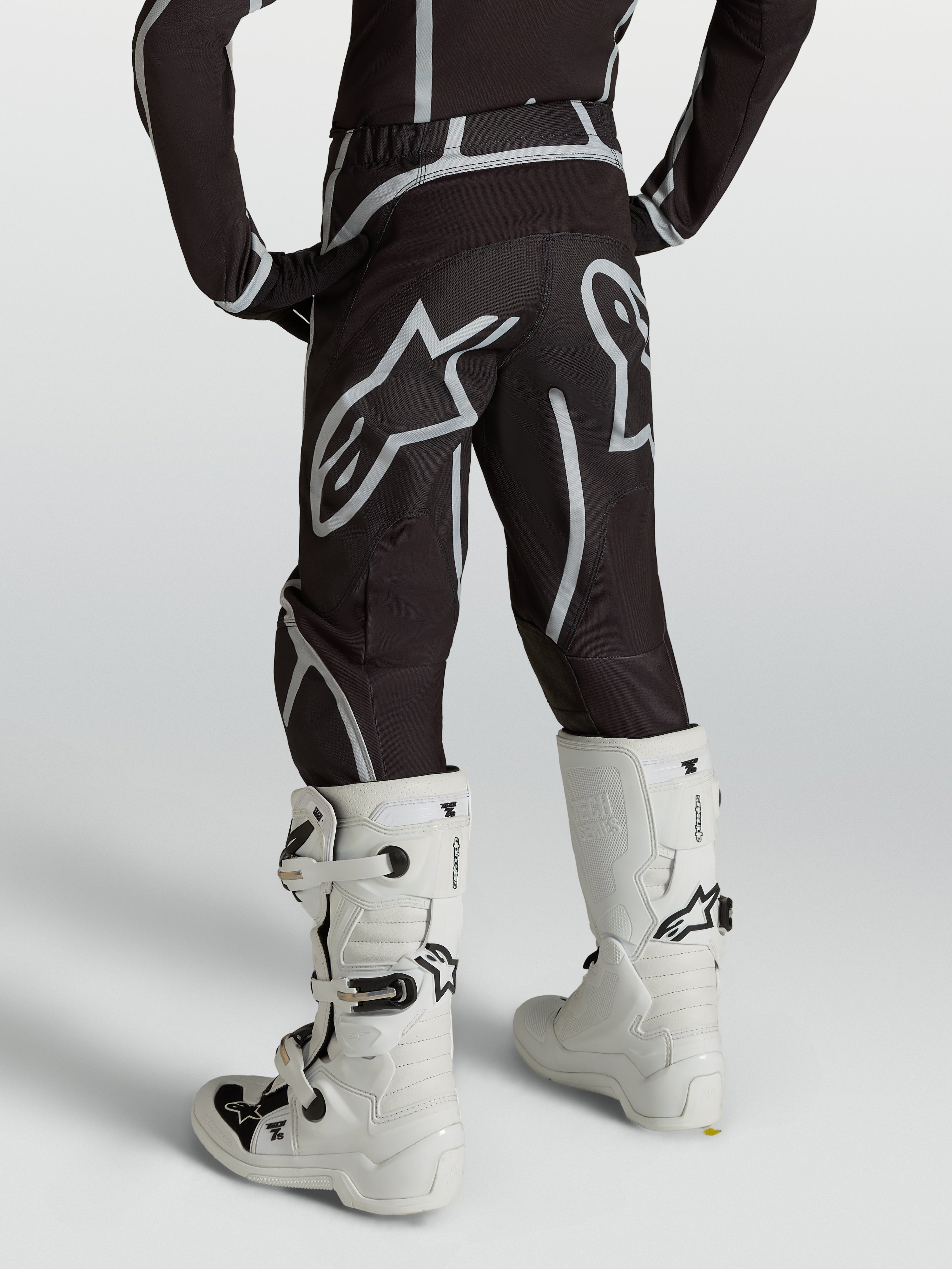 Alpinestars Jugend Fluid Apex V2 Hose, Motocross-Hose, Schwarz und Silber, Rückansicht mit weißen Motocross-Stiefeln.
