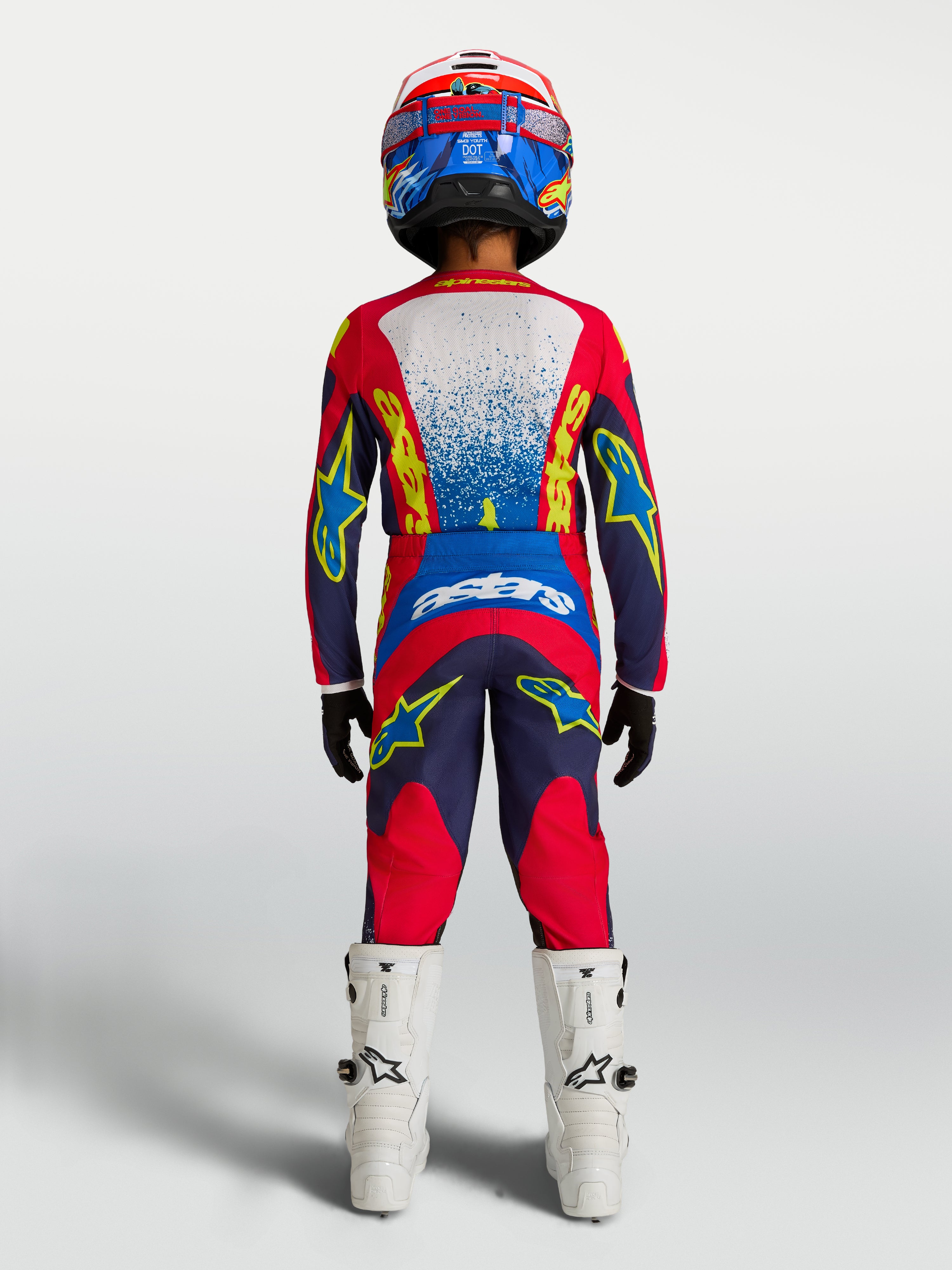 Alpinestars Jugend Fluid Drag Hose 2027, MX-Hose, Blau und Rot, Rückansicht mit Trikot, Helm und weißen Stiefeln.