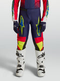 Alpinestars Jugend Fluid Drag Hose, Motocross-Hose für Kinder, Blau, Rot und Neongelb, getragen mit weißen Stiefeln.