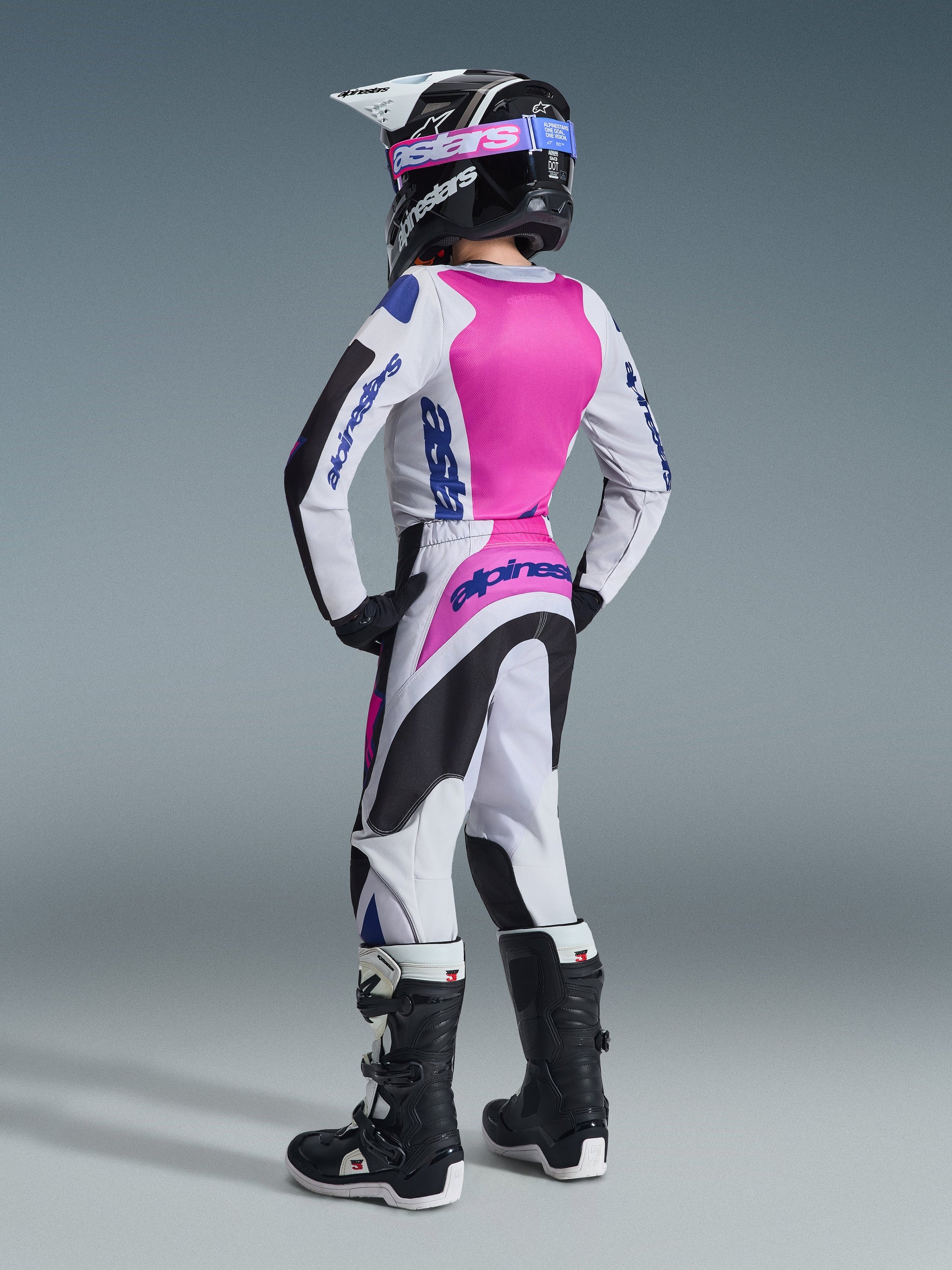 Alpinestars 2026 Youth Fluid Grid Hose, Motocross-Hose, Schwarz, Hellgrau und Lila, Rückansicht eines jungen Fahrers in kompletter, passender Rennausrüstung inklusive Trikot, Helm und Stiefeln, abgestimmtes Outfit für den Offroad-Rennsport