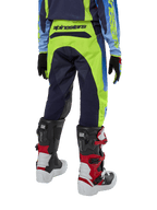 Alpinestars Youth 2024 Racer Hoen Hose, Motocross-Hose, Gelb Fluo und Blue Night Navy, Rückansicht mit markantem Alpinestars-Branding am Bund, getragen mit schwarz-roten Tech Series Stiefeln und passendem Trikot, strapazierfähige sportliche Passform für jugendliche Offroad-Fahrten