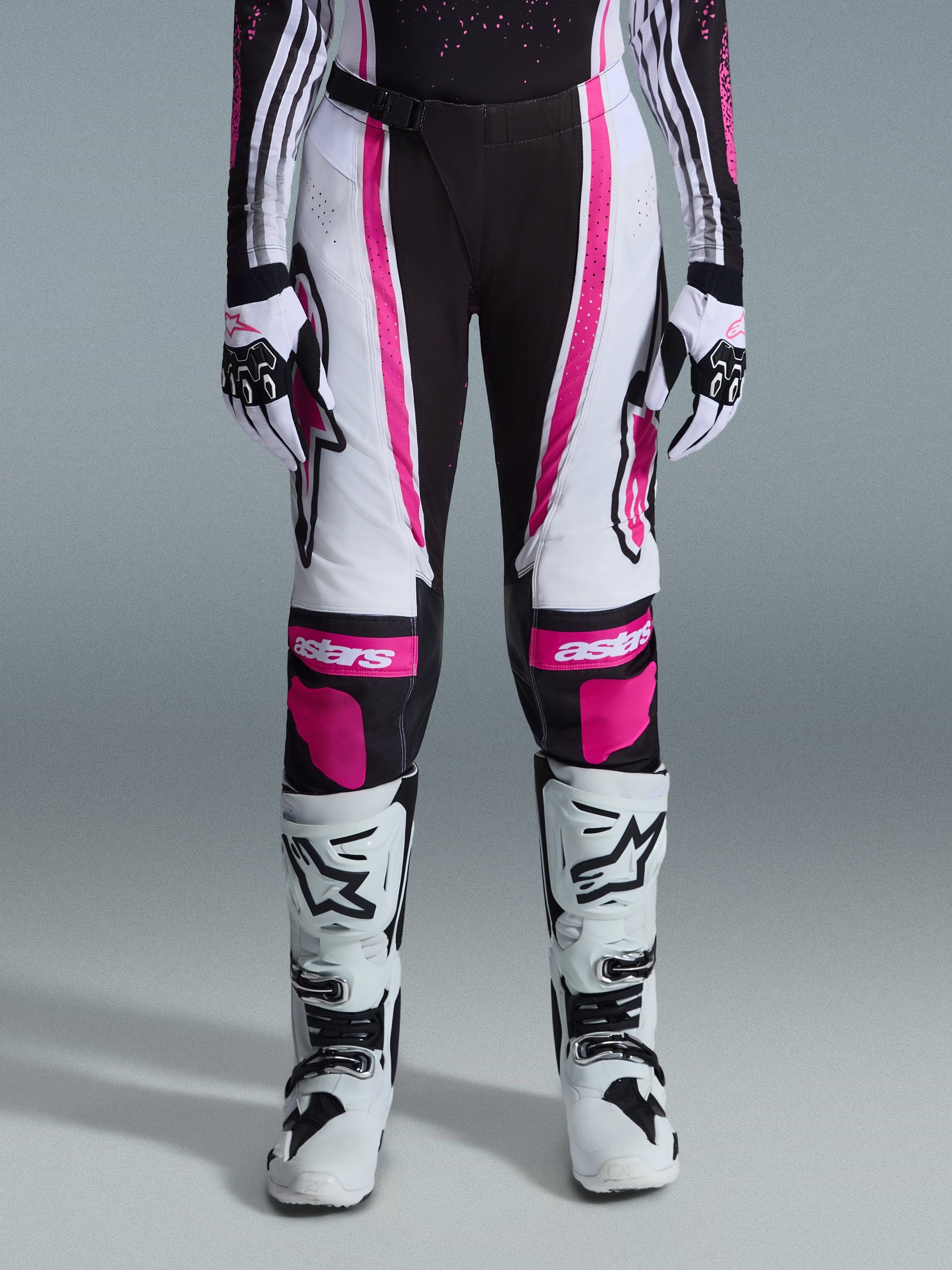 Alpinestars 2026 Woman Stella Techstar Nomur Pants, Motocross Pants, Black White and Fuchsia, worn with matching racing jersey, gloves, and white motocross boots, featuring bold pink graphics and astars logos on the knees, designed for high-level off-road competition.