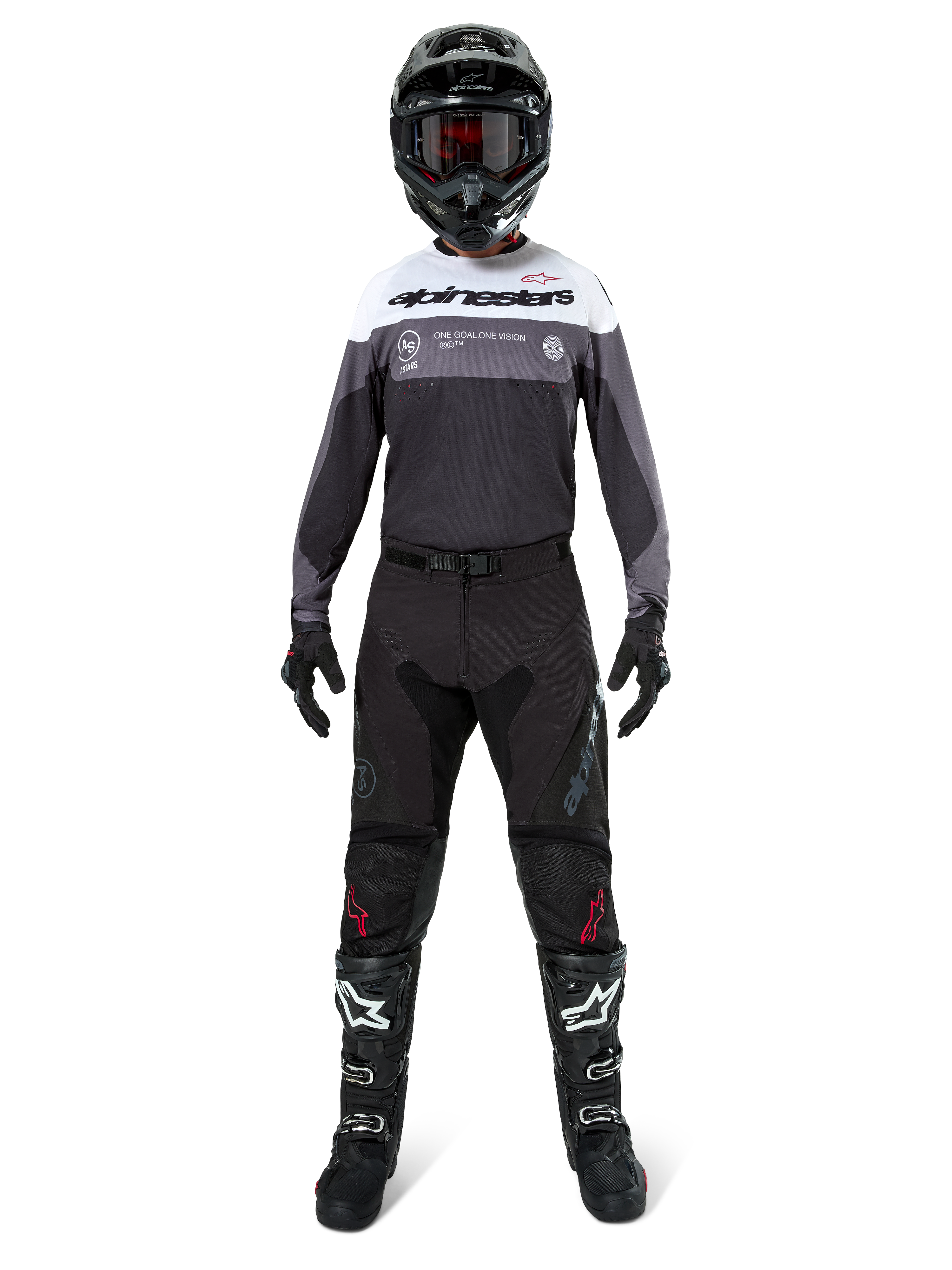 Motocross-Fahrer in kompletter Rennausrüstung, Pro-Dura Trikot in Black Magnet White mit weißem Brustbereich und grauen Akzenten, kombiniert mit schwarzer Hose, schwarzem Helm mit dunkler Brille, weiß-schwarzen Stiefeln und schwarzen Handschuhen, abgestimmtes Outfit für Enduro- und Offroad-Rennsport