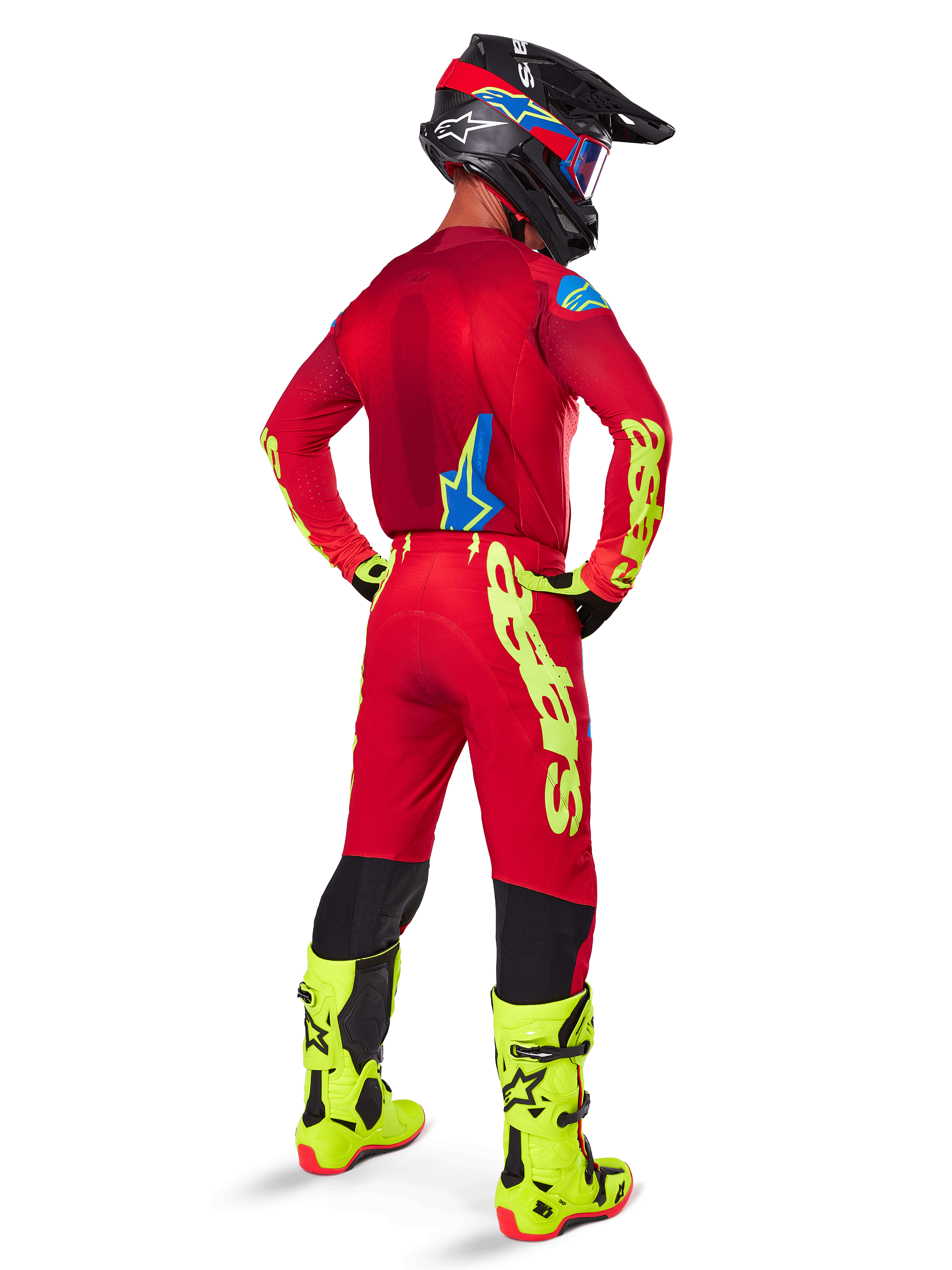 Motocross-Fahrer in der Rückansicht, trägt das Alpinestars 2025 Supertech Maker Trikot in Hellrot und Gelb Fluo, dazu passende Hose mit gelbem Branding, neongelbe Stiefel und einen schwarz-roten Helm, koordiniertes Outfit für den Profi-Offroad-Rennsport