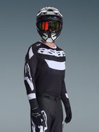 Motocross-Fahrer trägt das 2026 Racer Air Riway Trikot, schwarz-weißes Trikot mit „astars“-Logo, passender schwarz-weißer Helm mit orange verspiegelter Brille, schwarze Motocross-Hose und Handschuhe, abgestimmtes Outfit für den Offroad-Rennsport