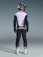 Rückansicht eines Motocross-Fahrers im 2026 Racer Air Riway Jersey in Schwarz und Weiß, mit atmungsaktivem Mesh-Rückeneinsatz, kombiniert mit passender schwarzer Motocross-Hose mit weißem „astars“-Branding, schwarz-weißem Helm und weißen Rennstiefeln.