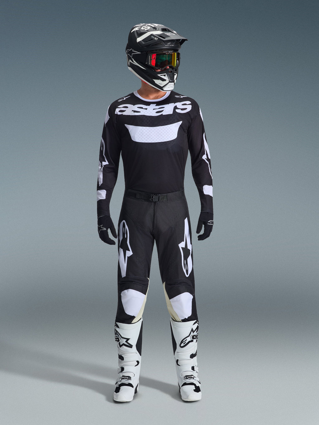 Motocross-Fahrer in kompletter Rennausrüstung, Alpinestars 2026 Racer Air Riway Trikot in Schwarz und Weiß mit „astars“-Logo auf der Brust, passende schwarze Hose mit weißen Akzenten, weiße Motocross-Stiefel und schwarz-weißer Helm mit Brille, professionell abgestimmtes Offroad-Outfit