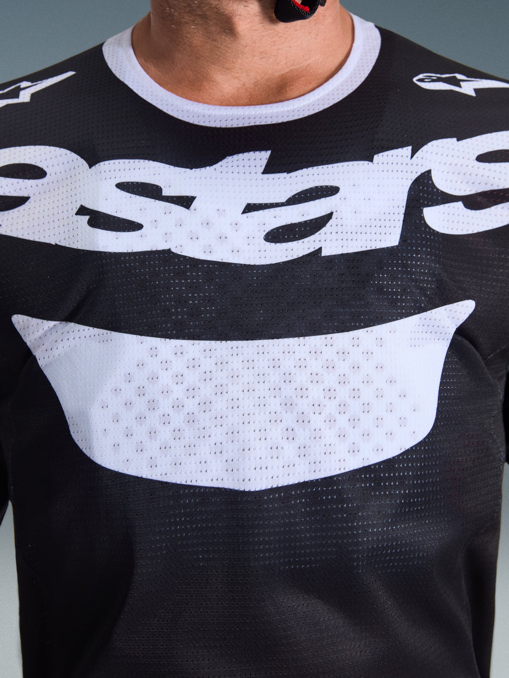 Alpinestars 2026 Racer Air Riway Trikot, Motocross-Trikot, Schwarz und Weiß, Nahaufnahme des Brustbereichs mit großem weißem Logo, detaillierte Textur des Mesh-Gewebes für Luftzirkulation, technische atmungsaktive Ausrüstung für den Offroad-Einsatz