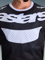 Alpinestars 2026 Racer Air Riway Trikot, Motocross-Trikot, Schwarz und Weiß, Nahaufnahme des Brustbereichs mit großem weißem Logo, detaillierte Textur des Mesh-Gewebes für Luftzirkulation, technische atmungsaktive Ausrüstung für den Offroad-Einsatz