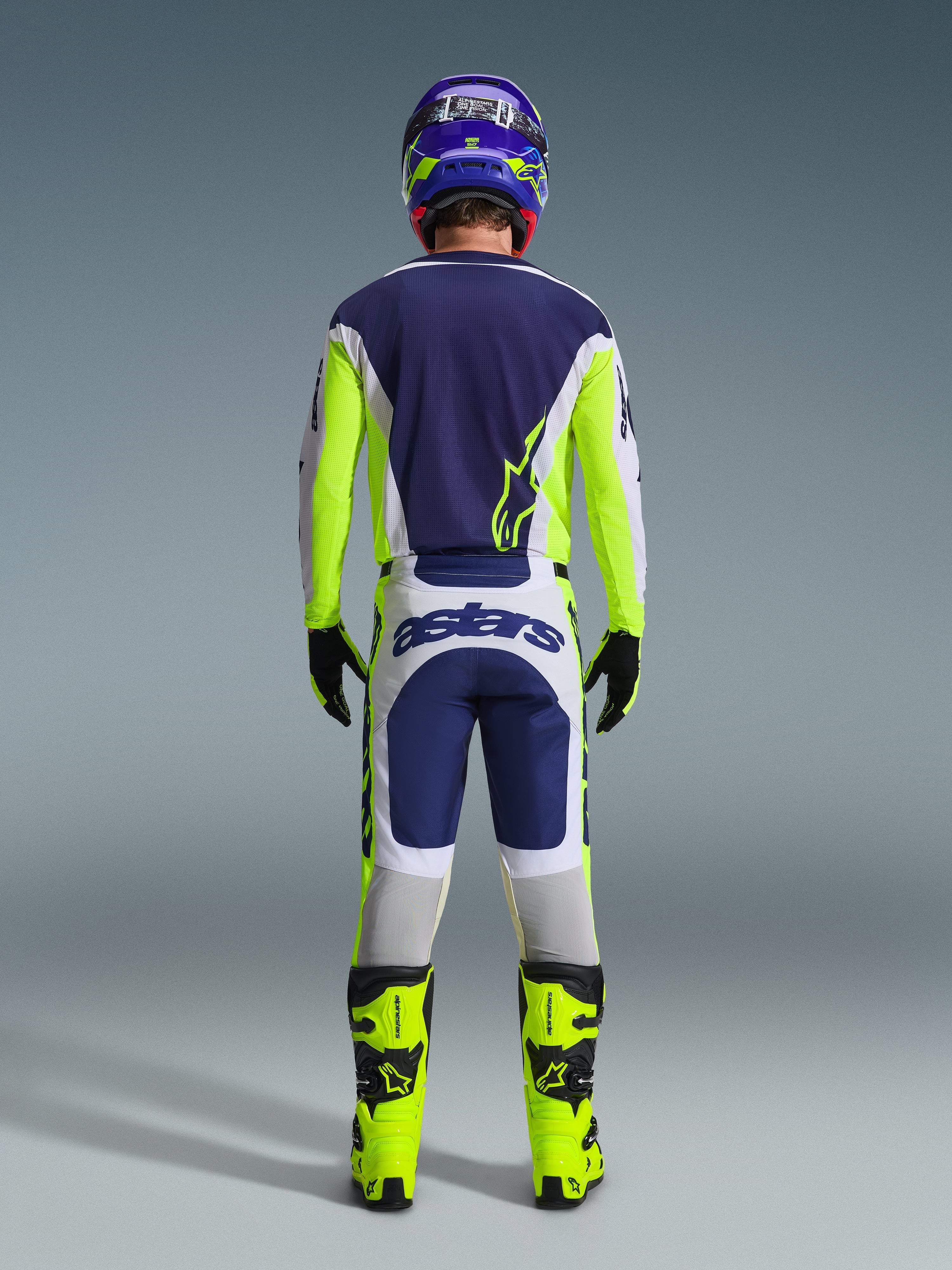 Back view of a motocross rider wearing the Alpinestars 2026 Racer Air Riway Jersey and matching pants in Light Gray Yellow Fluo Blue, paired with bright yellow fluo boots and a coordinated helmet, showing a complete off-road racing gear set.