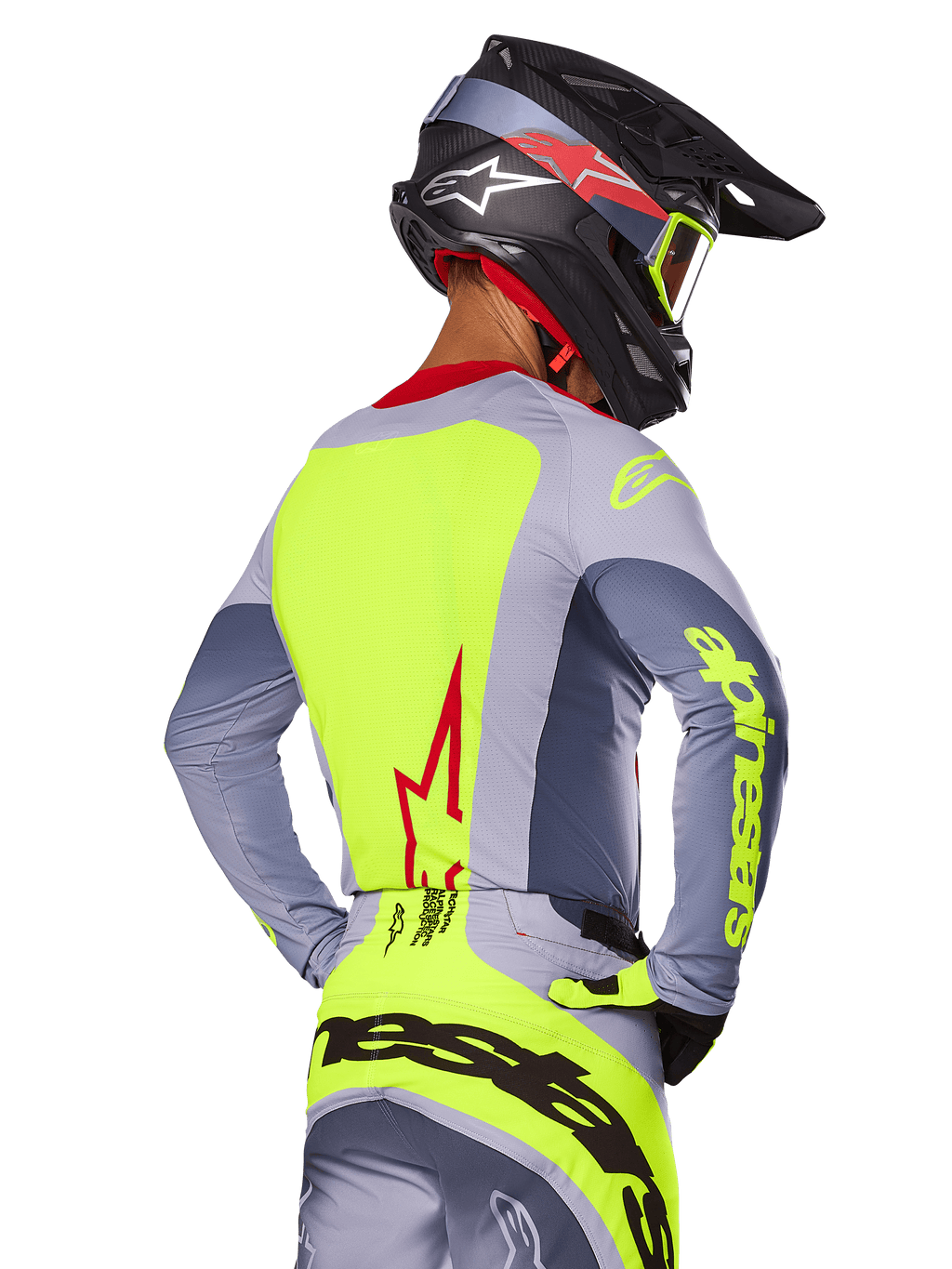 Alpinestars 2025 Techstar Melt Trikot, Bright Red Gray, Rückansicht eines Motocross-Fahrers in grauer und neongelber Rennausrüstung, rotes Stern-Logo auf dem Rücken, passender schwarz-roter Helm, Performance-Offroad-Bekleidung