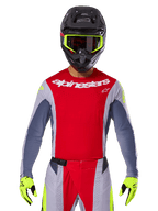 Motocross-Fahrer mit 2025 Techstar Melt Jersey und passender Hose, Hellrot und Grau mit weißem Alpinestars-Branding, schwarzer Helm mit neongelber Brille, passende neongelbe Handschuhe, belüftete Performance-Ausrüstung für Offroad-Rennen