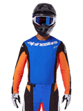 Alpinestars 2025 Techstar Melt Trikot, Motocross-Jersey, Blau und Orange mit schwarzen Seiteneinsätzen, getragen mit schwarzem Helm und blauer Brille, mit atmungsaktiven lasergeschnittenen Perforationen auf der Brust, athletische Rennpassform für Offroad-Performance